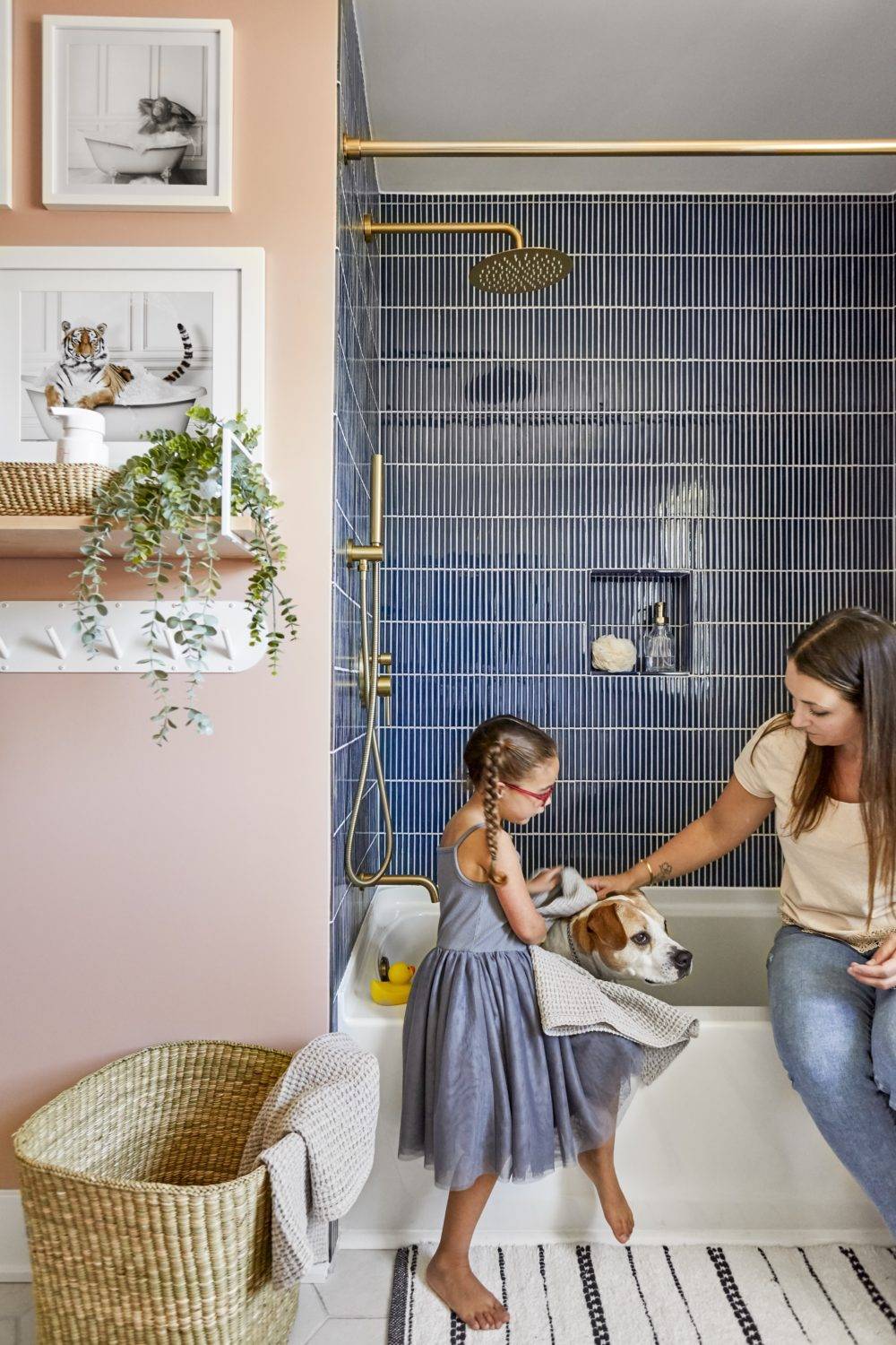 Kids bathroom with pink walls and navy blue stacked shower tile