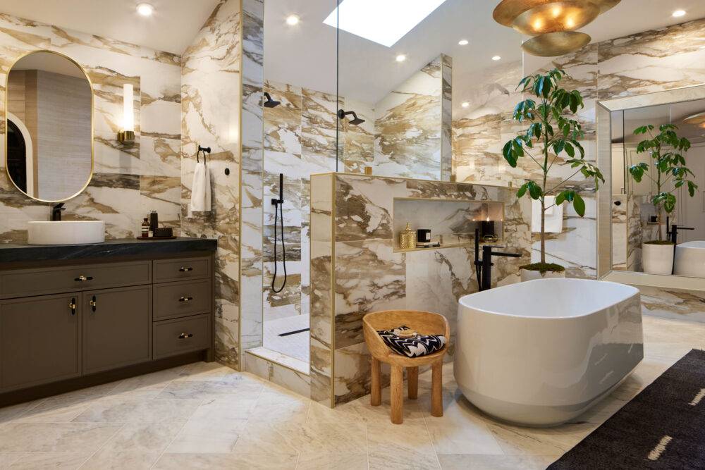 Large bathroom with white marble floors and white with dramatic ochre and gold veining large-format marble-look porcelain tile walls.