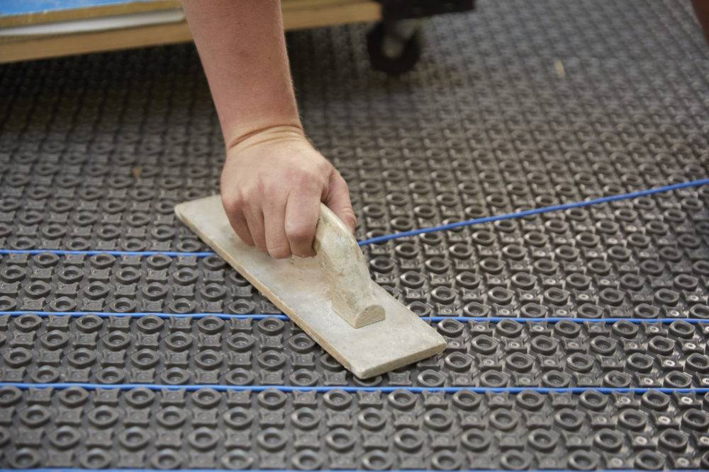 In-floor heat wire being installed in membrane