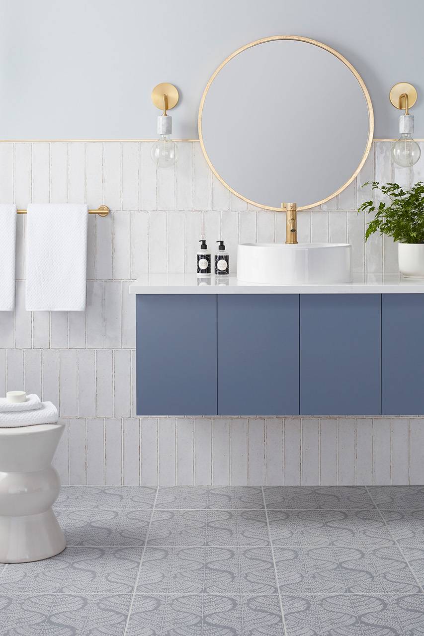 Bathroom with white subway tile wall and blue with white floral patterned floor tile. 