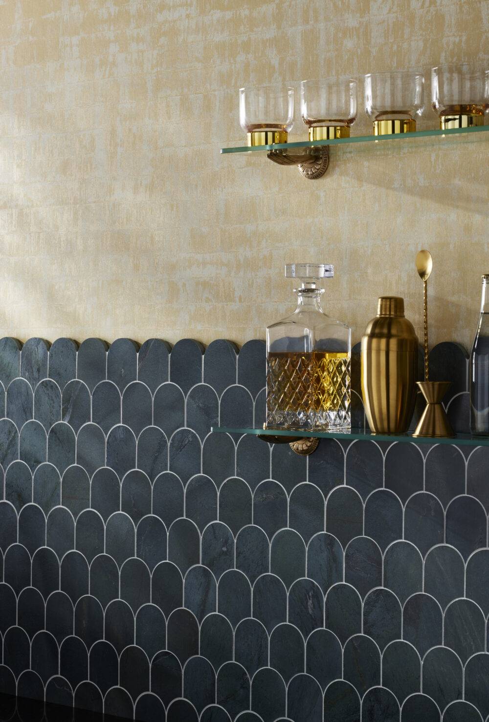 Scalloped tile half wall with glass shelves with glasses and bar items.