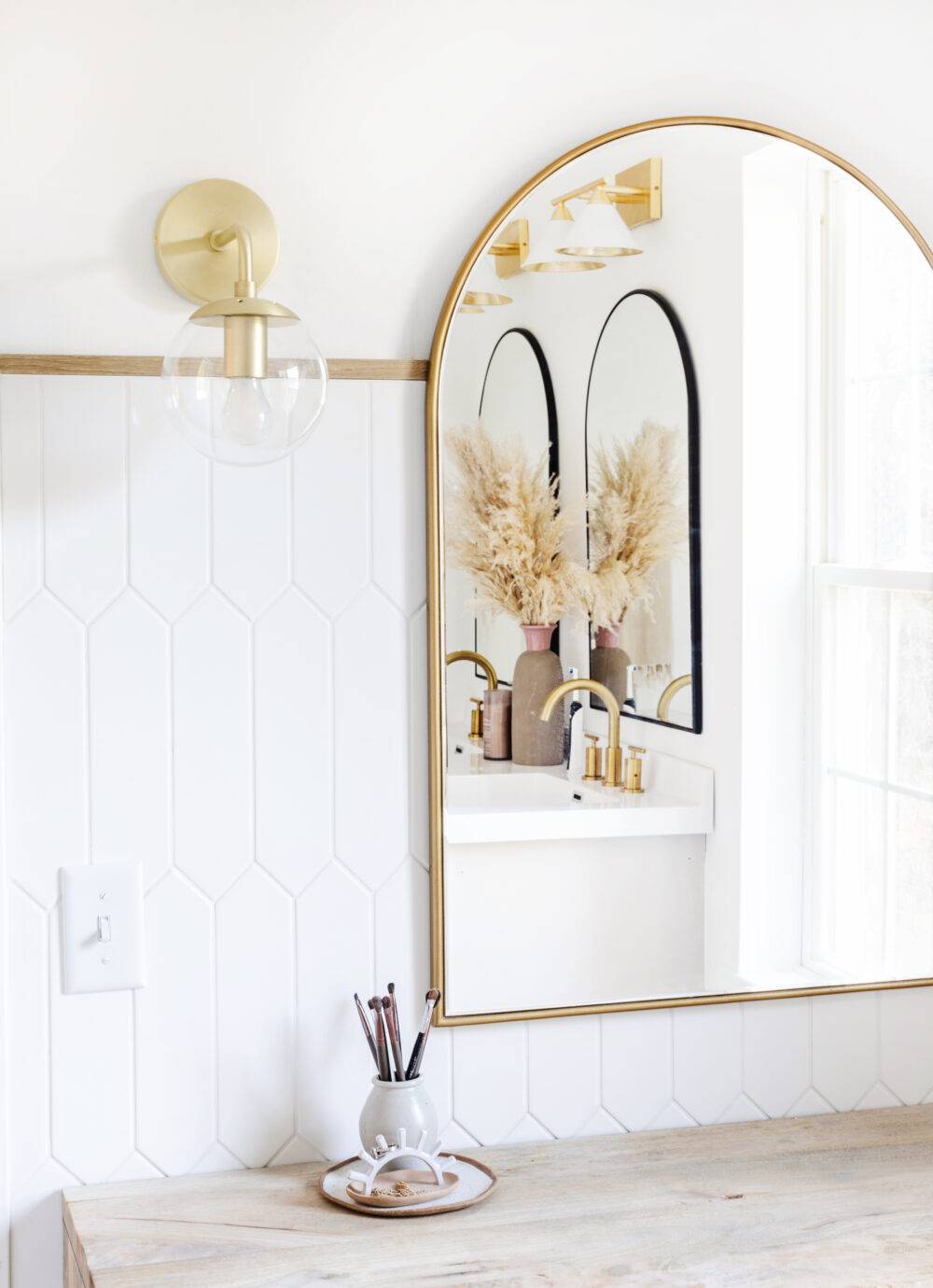 Bathroom with white picket tile wall and gold mirror.