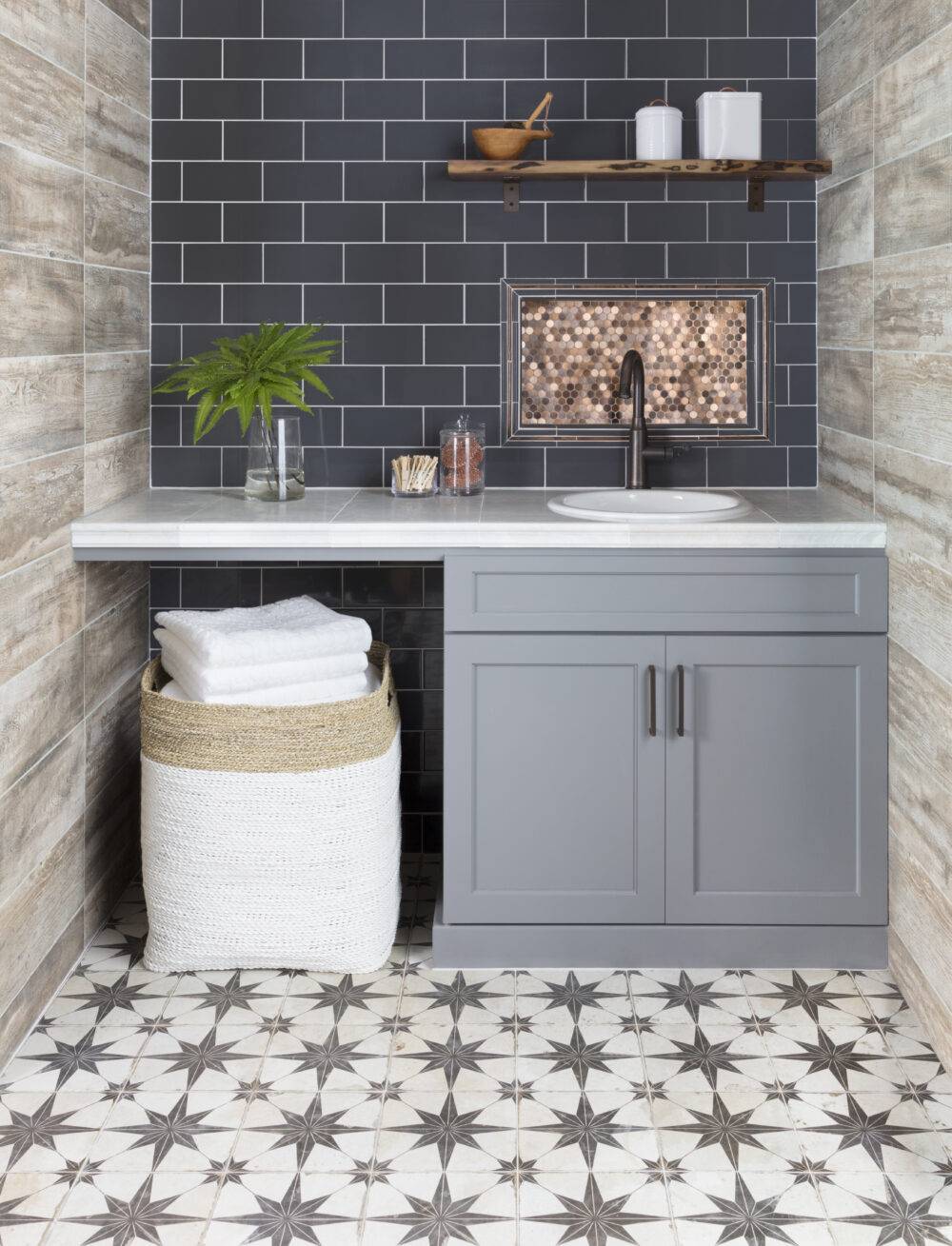 Modern farmhouse style laundry room with blue subway tile and wood-look tile on the walls and encaustic-look tile on the floor.