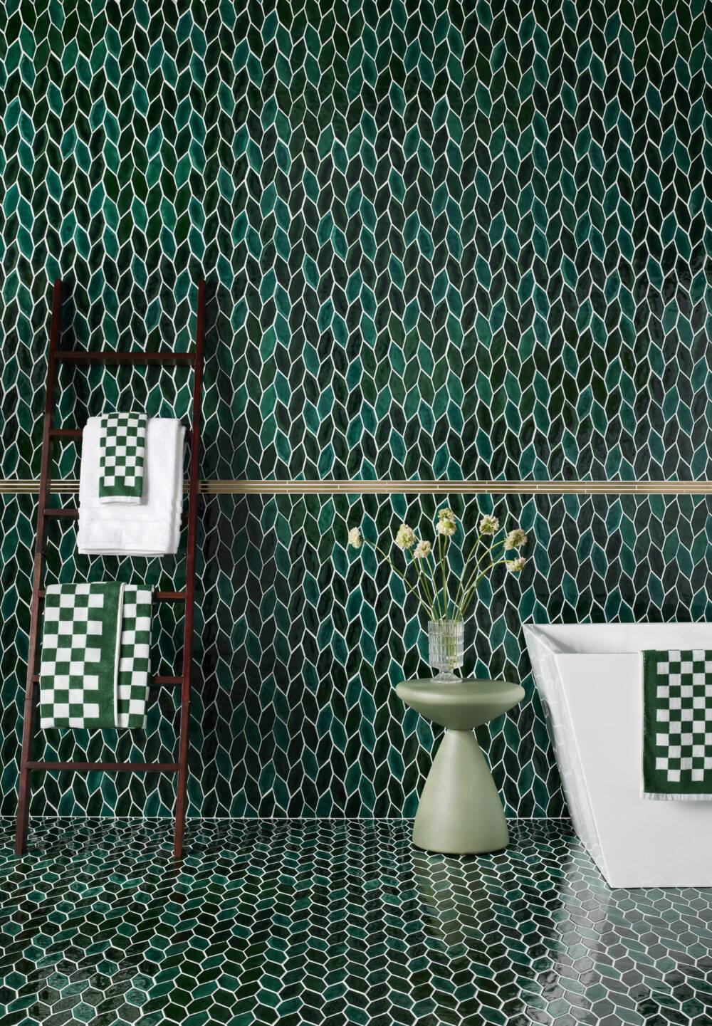 Green leaf mosaic bathroom wall with ladder towel rack.