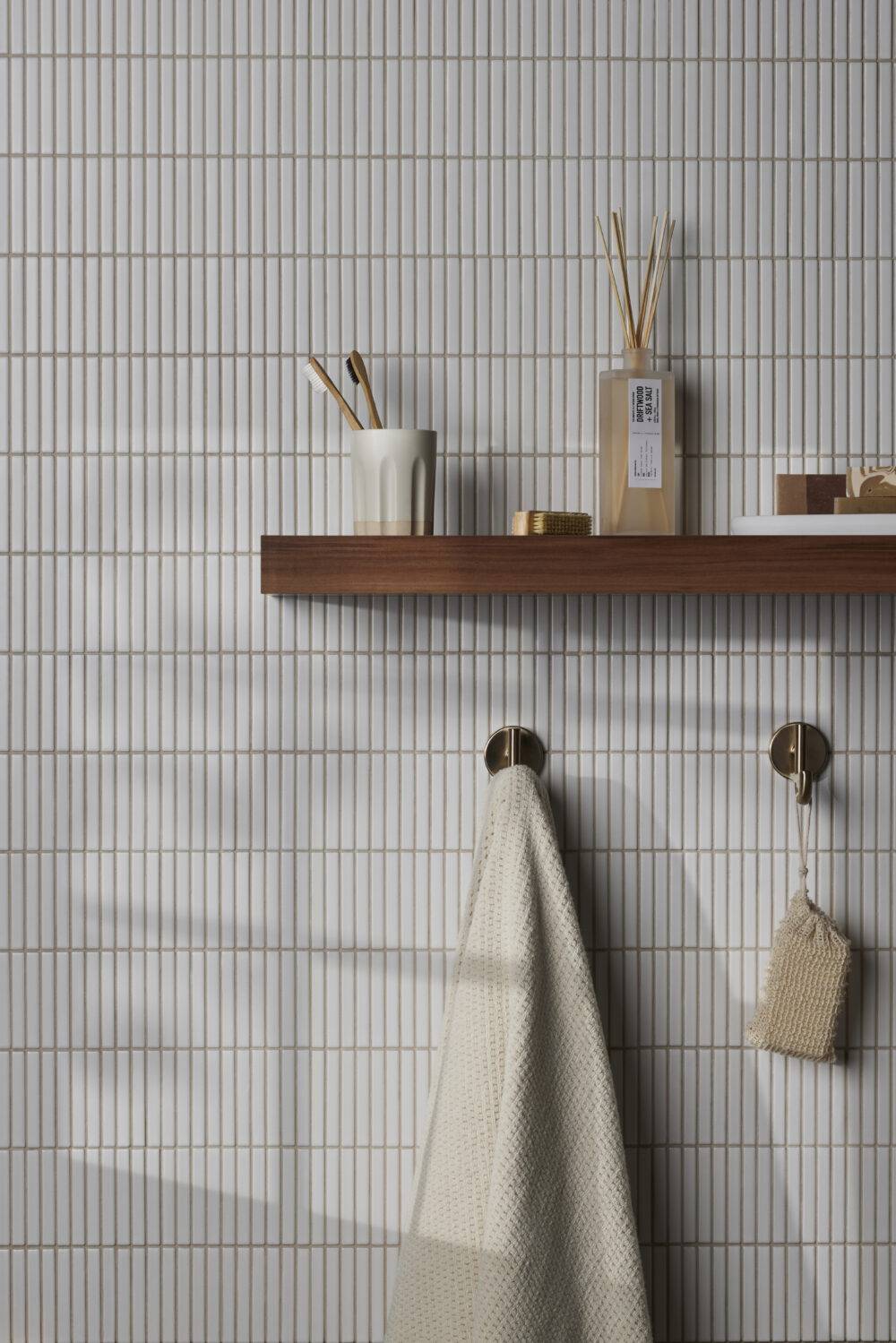 Tiled bathroom wall featuring white thin, elongated mosaic tile that imitates a kit kat shape.