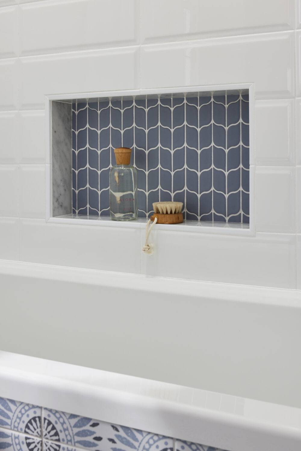 Blue leaf-shaped tile shower niche with soap and brush.