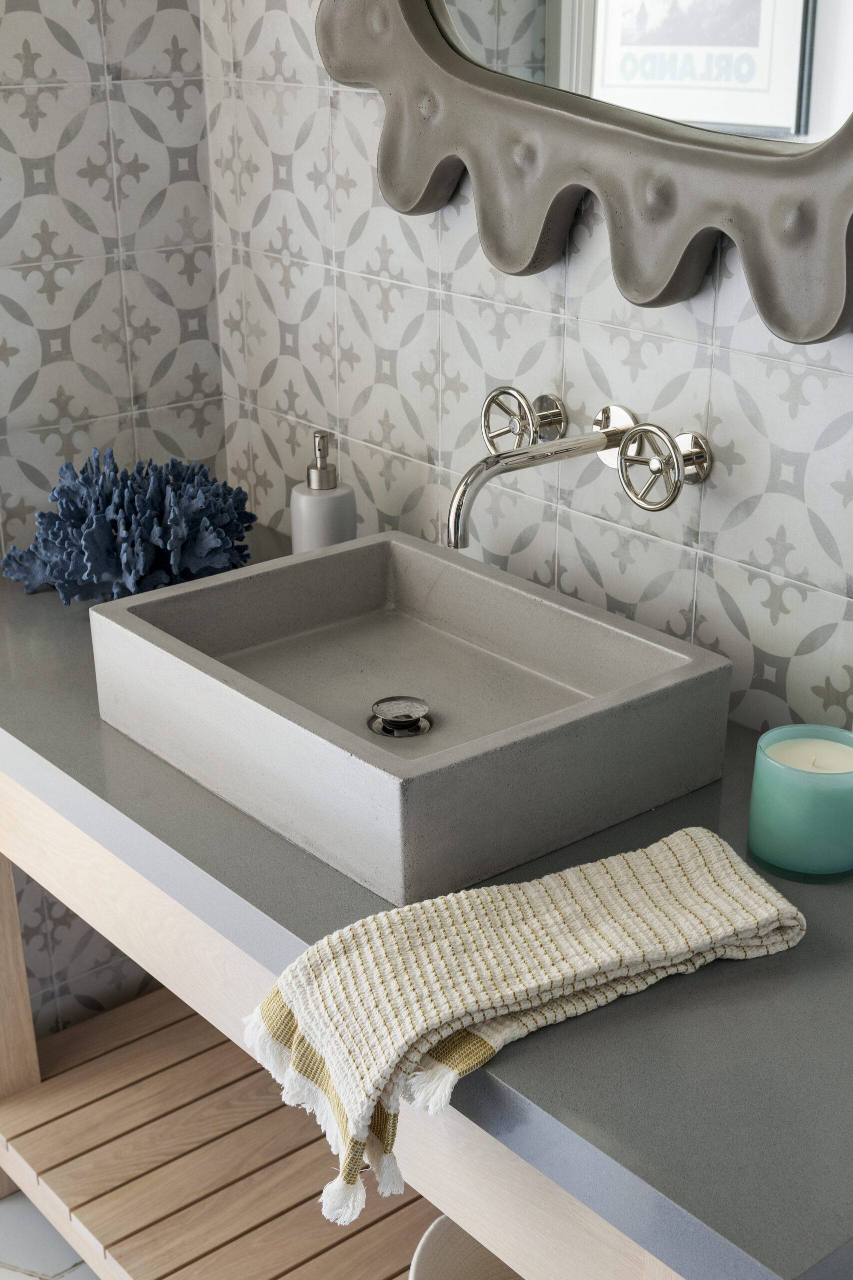 Close-up of pool room sink with blue coral and candle. Featuring Decora Redondo tile.