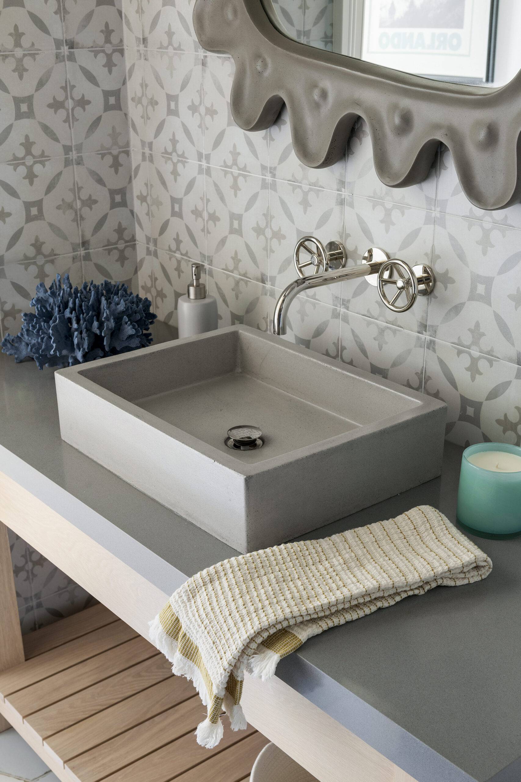 Close-up of pool room sink with blue coral and candle. Featuring Decora Redondo tile. 