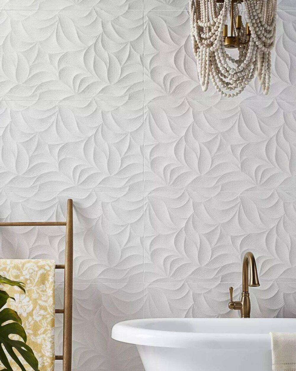 Textured ceramic white tile on wall in bathroom behind soaker tub.  Wood towel rack and white tub.  Copper toned faucet.