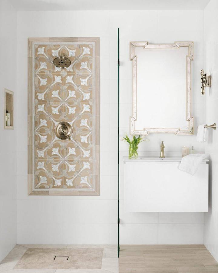 Bathroom area with walk in shower and floating vanity. Shower and wainscoting tile are rectangular raised glaze white surfaces . Shower wall has a framed out tulip mosaic tile and matching niche. Flooring is marble and limestone tiles in similar tones.