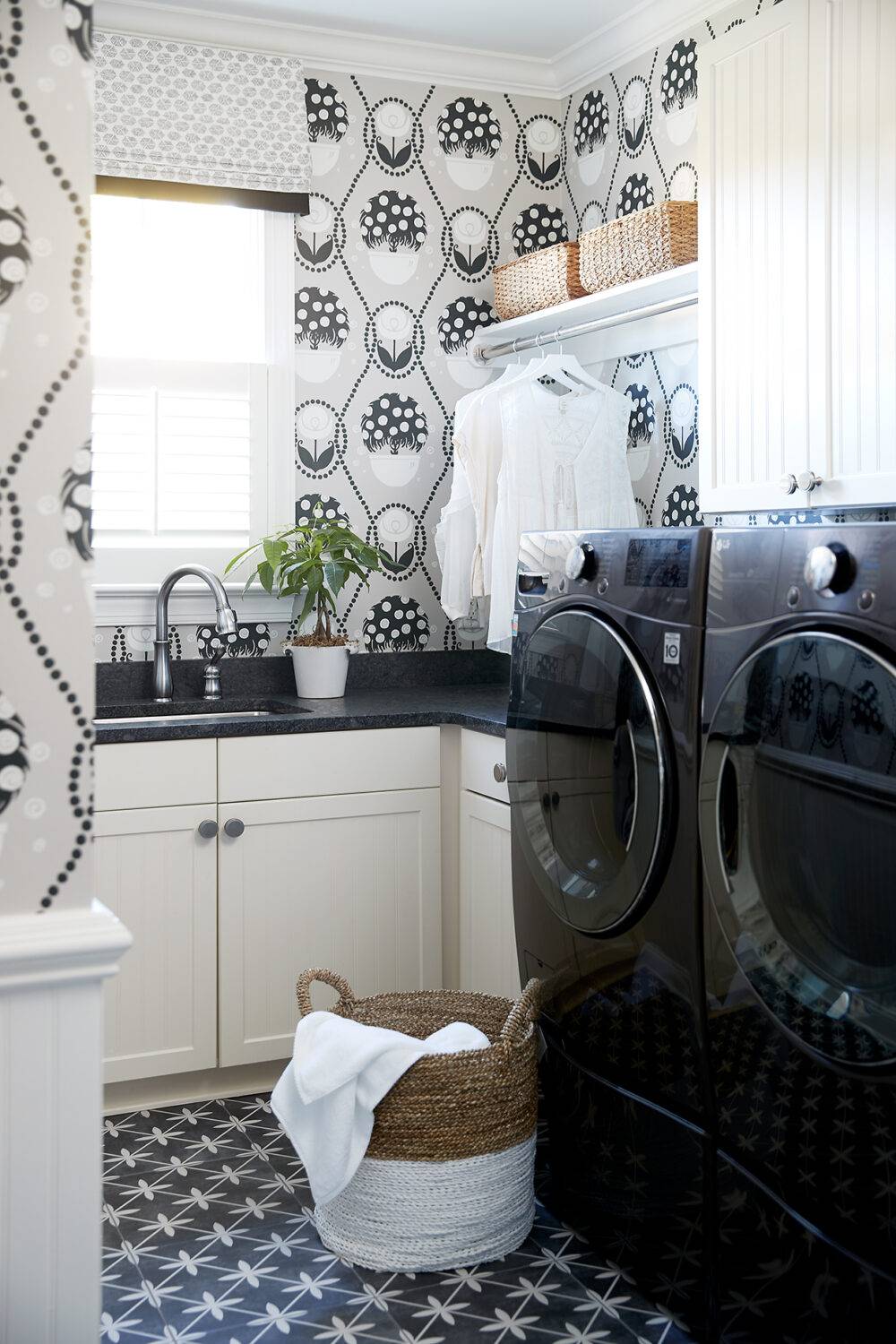 Laundry room with black and white patterned wallpaper and black with white star shapes tile floor.